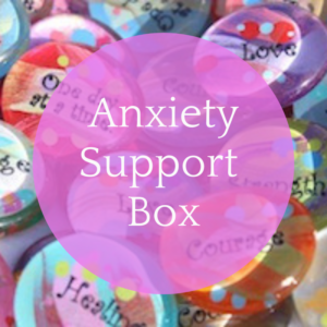 Anxiety support box: text on pink bubble over photograph of pile of colourful glass palm stones with empowering words on them